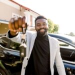 Man smiling and holding car keys, representing car ownership through a car loan program.