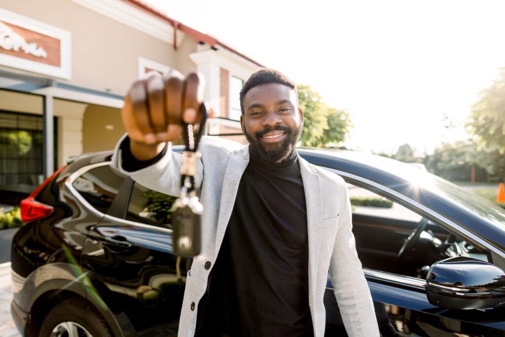 Man smiling and holding car keys, representing car ownership through a car loan program.