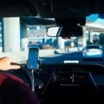 A man using a mobile phone for navigation while driving a car, highlighting the ease of use of car share programs.