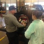 Montgomery County Fire Rescue Service personnel assist a parent with infant car seat installation, highlighting the Montgomery County Car Seat Program.