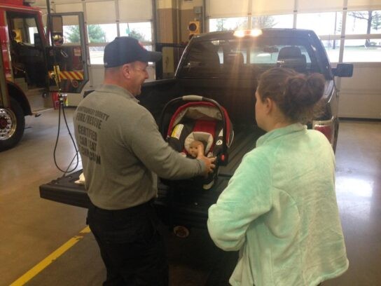 Montgomery County Fire Rescue Service personnel assist a parent with infant car seat installation, highlighting the Montgomery County Car Seat Program.