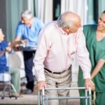 A nurse assists a senior resident with a walker, highlighting the importance of care in long-term facilities.