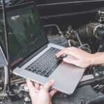 Mechanic reprogramming a car computer using a diagnostic scanner, illustrating the process of updating vehicle software.