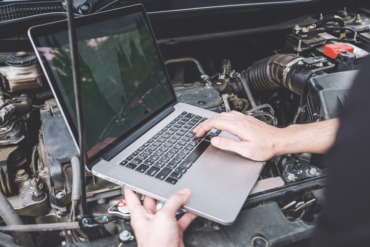 Mechanic reprogramming a car computer using a diagnostic scanner, illustrating the process of updating vehicle software.