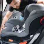 A parent securing a child in a car seat, emphasizing child passenger safety and the importance of free car seat programs.