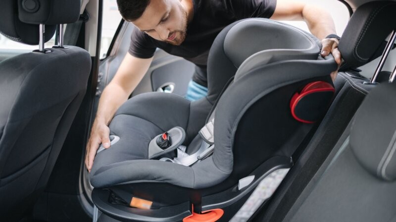 A parent securing a child in a car seat, emphasizing child passenger safety and the importance of free car seat programs.